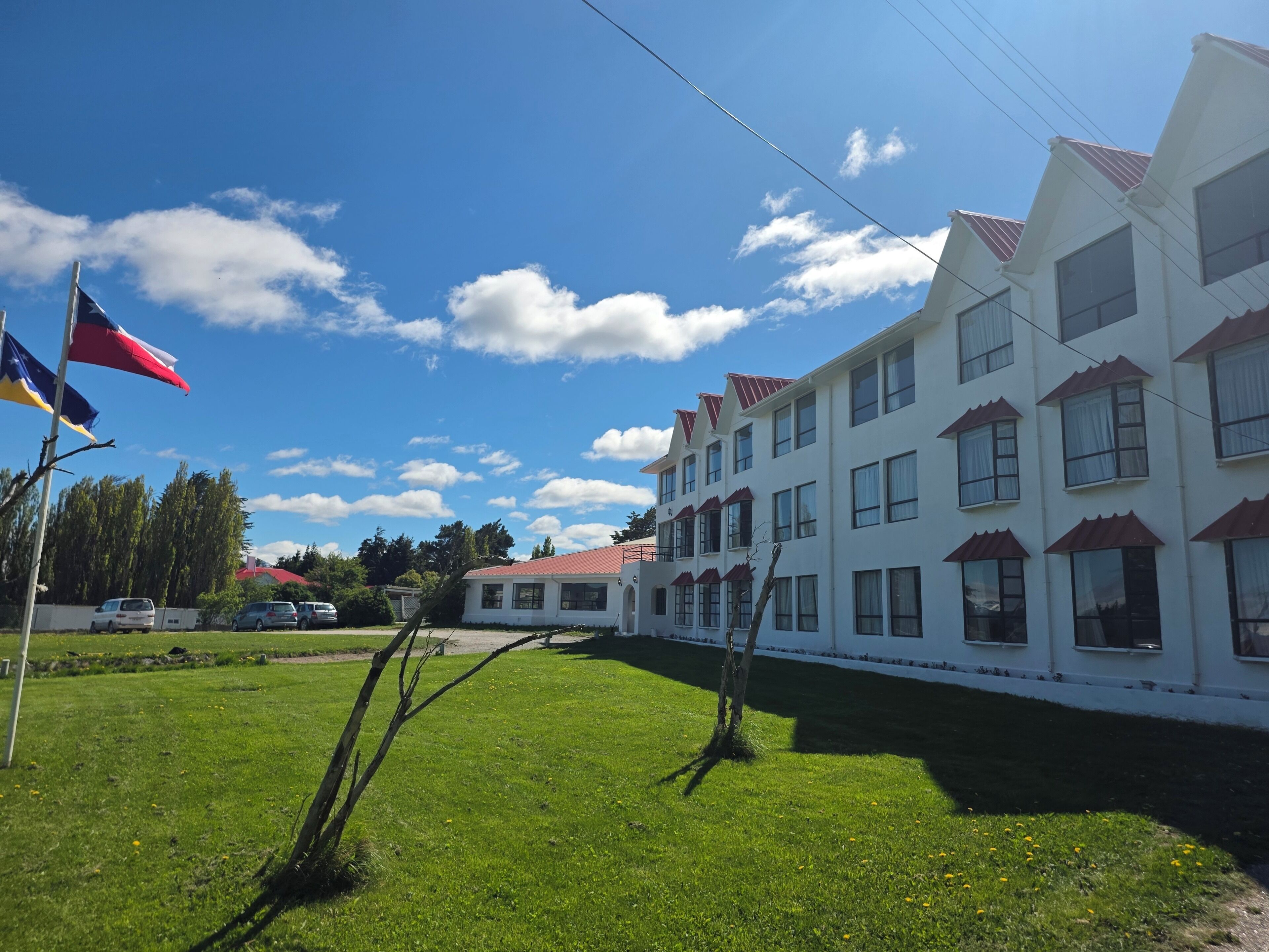 A multi-story building with a red roof and white walls, featuring multiple windows and balconies.
