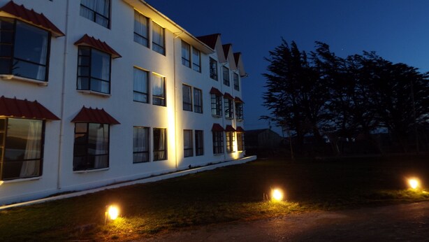 A multi-story building with a white facade and red roof accents. - Hotel HD Natales (Natales)