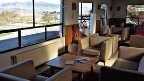 A room with large windows, a telescope, and several chairs and tables. - Hotel HD Natales (Natales)