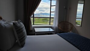 A hotel room with a bed, a small table, a chair, and a window offering a mountain view. - Hotel HD Natales (Natales)