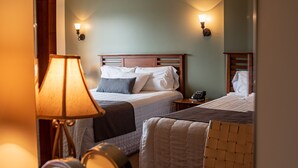 Ein Hotelzimmer mit zwei Betten, einem Nachttisch mit Lampe, einem Telefon und einer Wandleuchte.