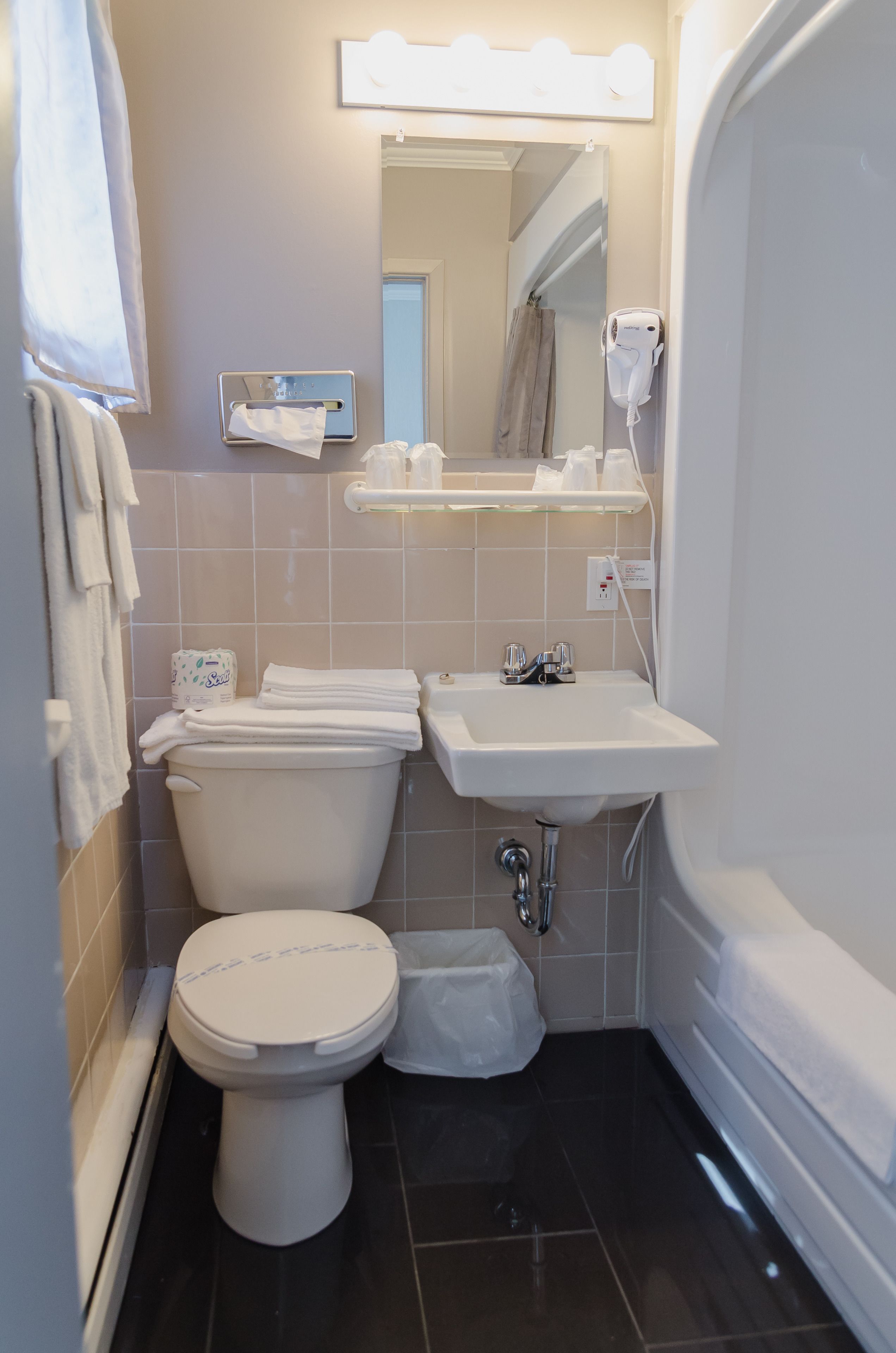 A compact bathroom with a toilet, sink, and a shower area.