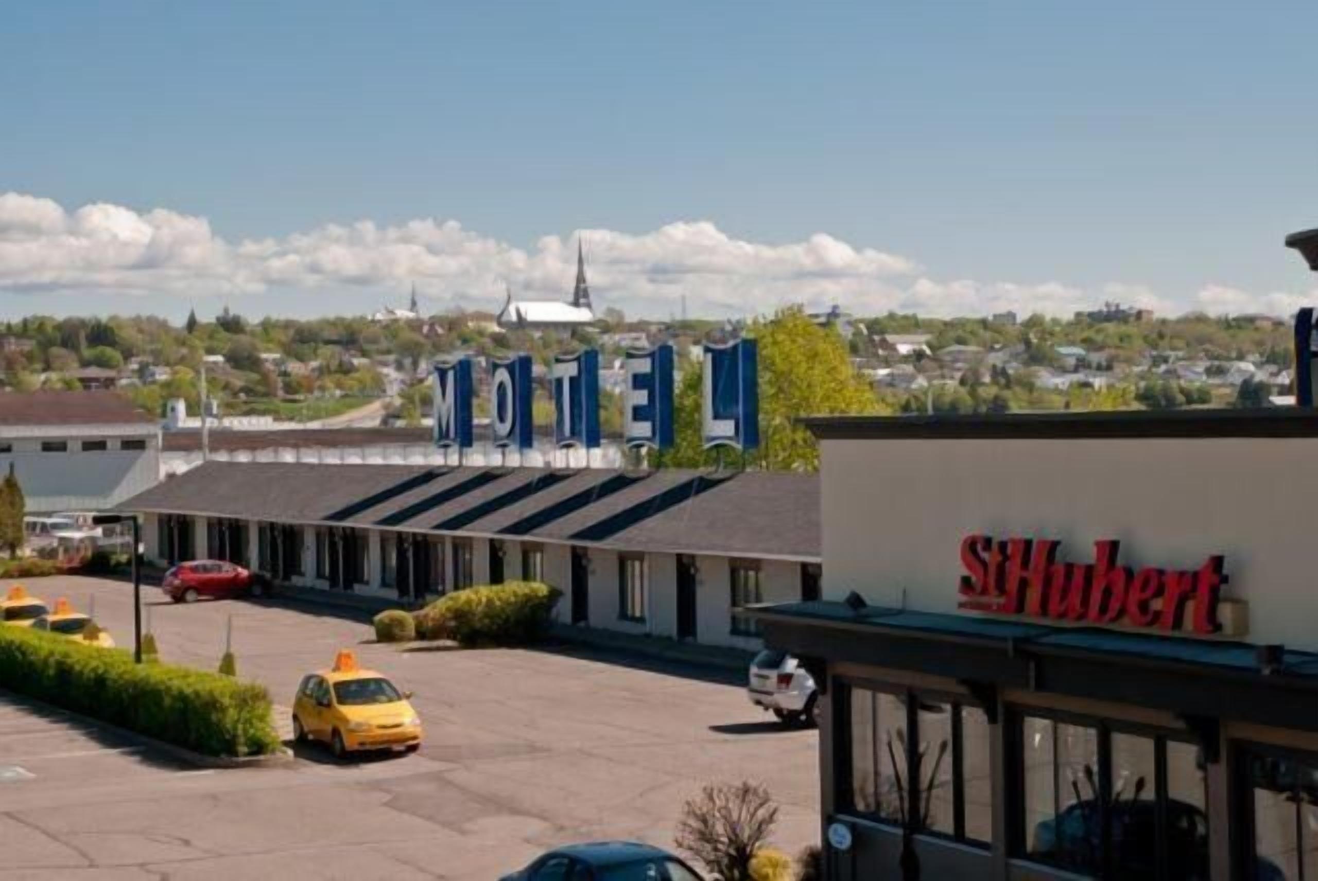 A motel with a sign reading "MOTEL" and a separate sign for "St. Hubert".