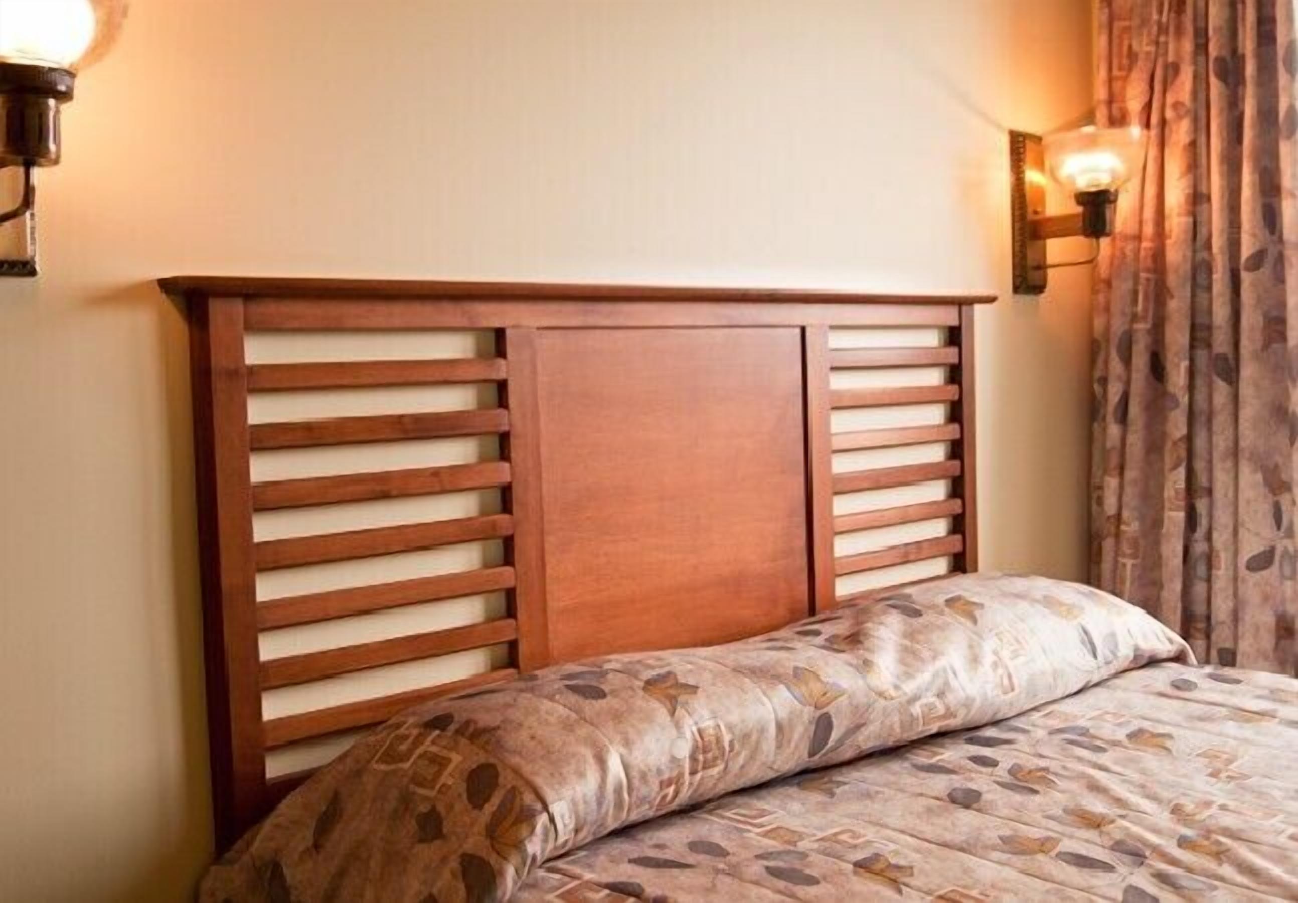 A bed with a wooden headboard and a patterned pillow.
