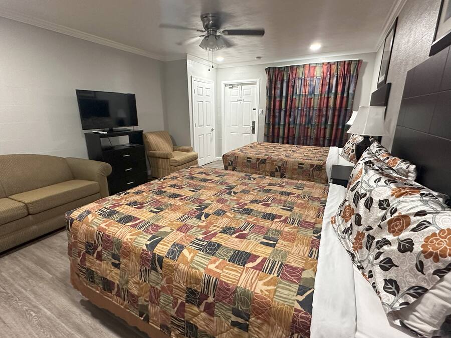 Ein Hotelzimmer mit einem großen Bett, einer Couch, einem Fernseher und einem Deckenventilator.