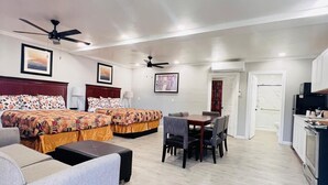 A spacious living area with a sofa, a dining table with chairs, and a kitchen area with a microwave and stove. - Sunshine Inn & Suites Venice, FL (Venice)
