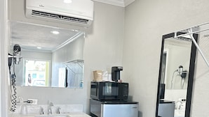 A compact kitchen with a white countertop, a stainless steel refrigerator, a microwave, and a coffee maker. - Sunshine Inn & Suites Venice, FL (Venice)
