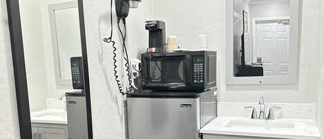 A compact kitchenette with a refrigerator, microwave, coffee maker, and a sink.