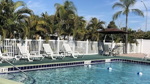 A swimming pool with white lounge chairs and a white fence. - Sunshine Inn & Suites Venice, FL (Venice)