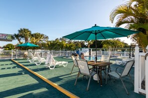 A poolside area with lounge chairs, a table, and umbrellas.
