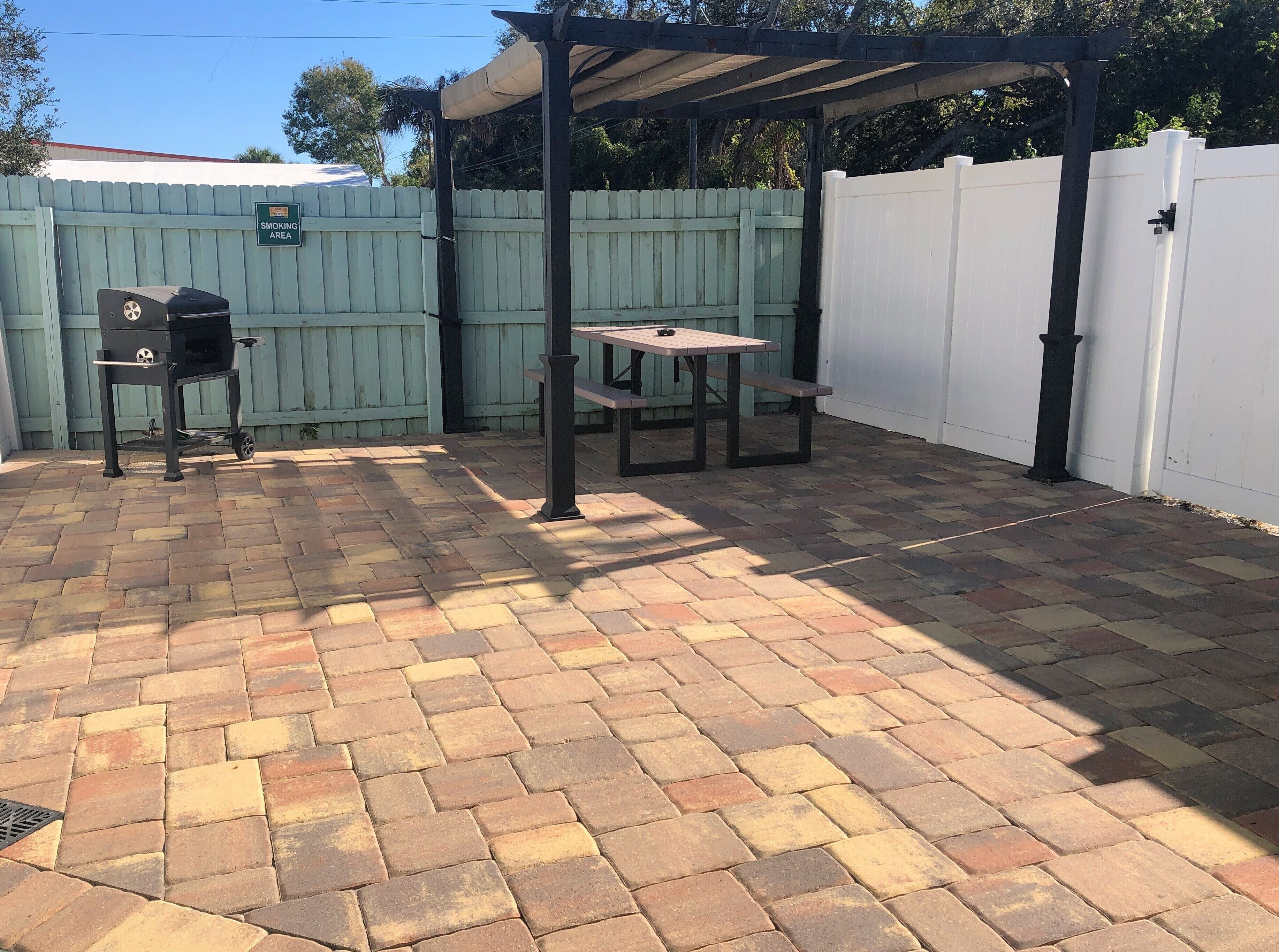 A patio area with a grill, picnic table, and covered seating.
