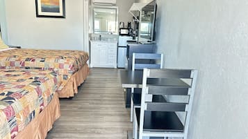 A bedroom with a bed, a desk, and a chair. There is a mirror above the desk and a picture on the wall.