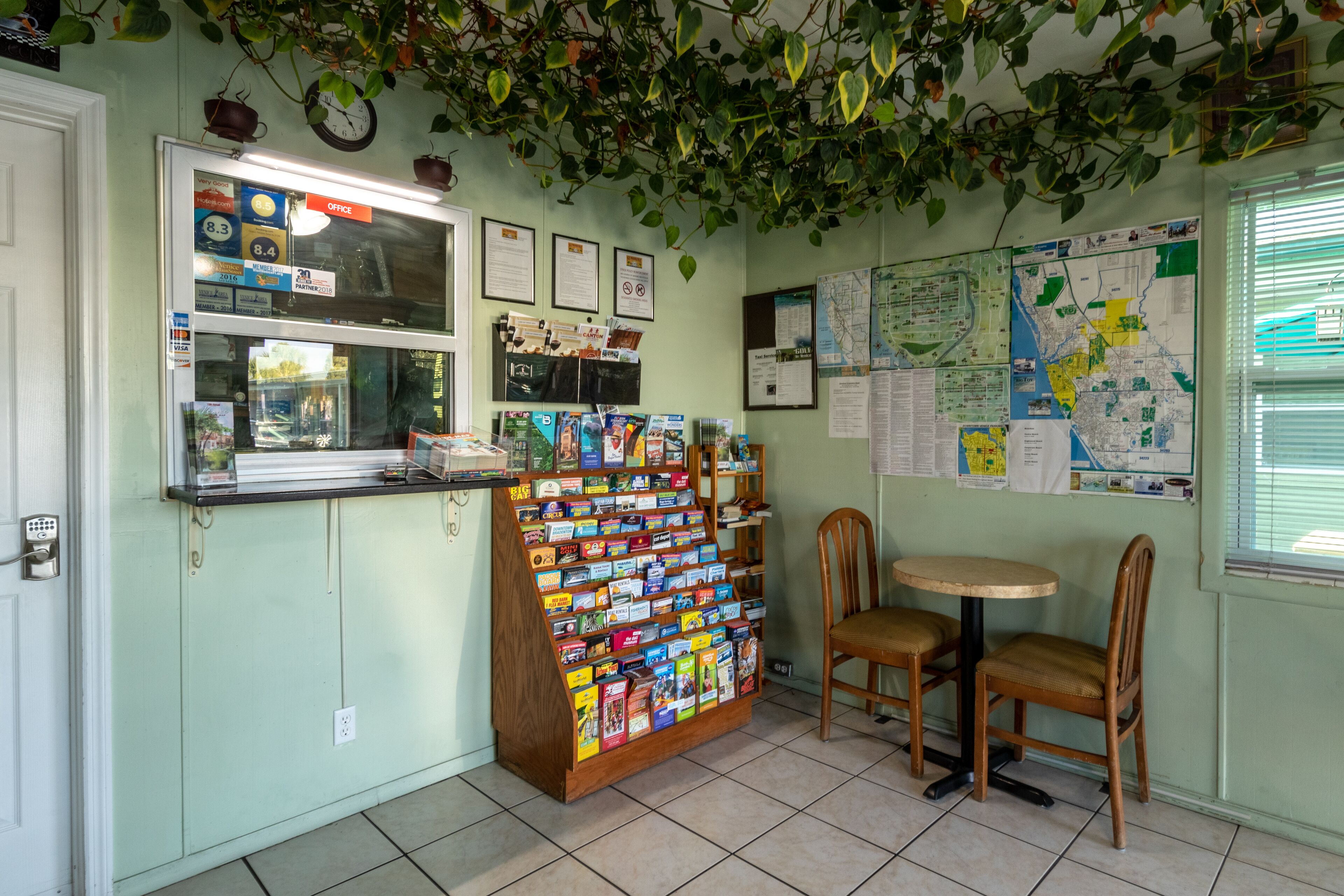 A small office with a bulletin board, a display of postcards, and a map on the wall.