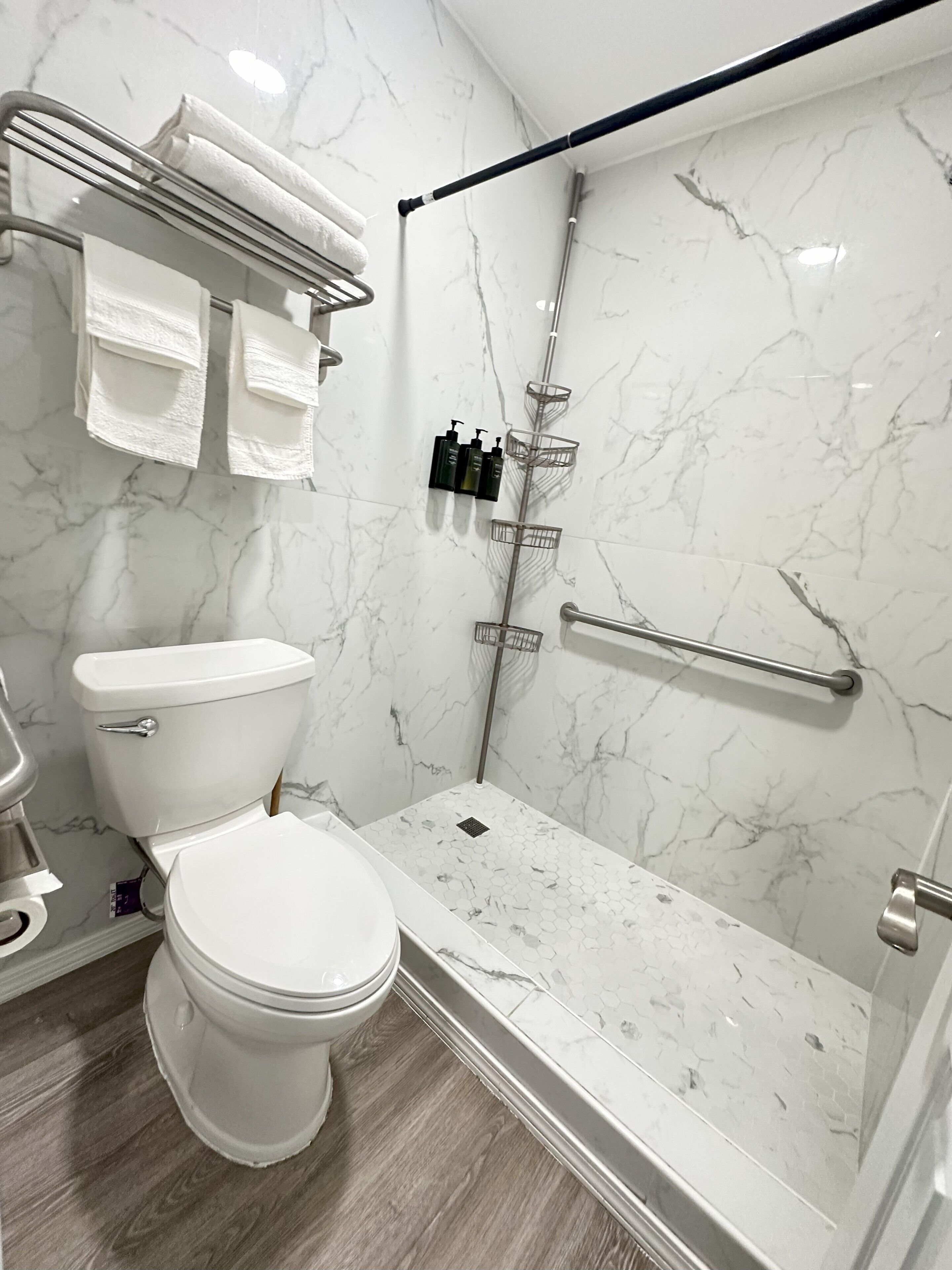 A modern bathroom with a toilet, shower, and marble walls.