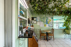 A small, cozy bookstore with a wooden counter, two chairs, and a map on the wall.