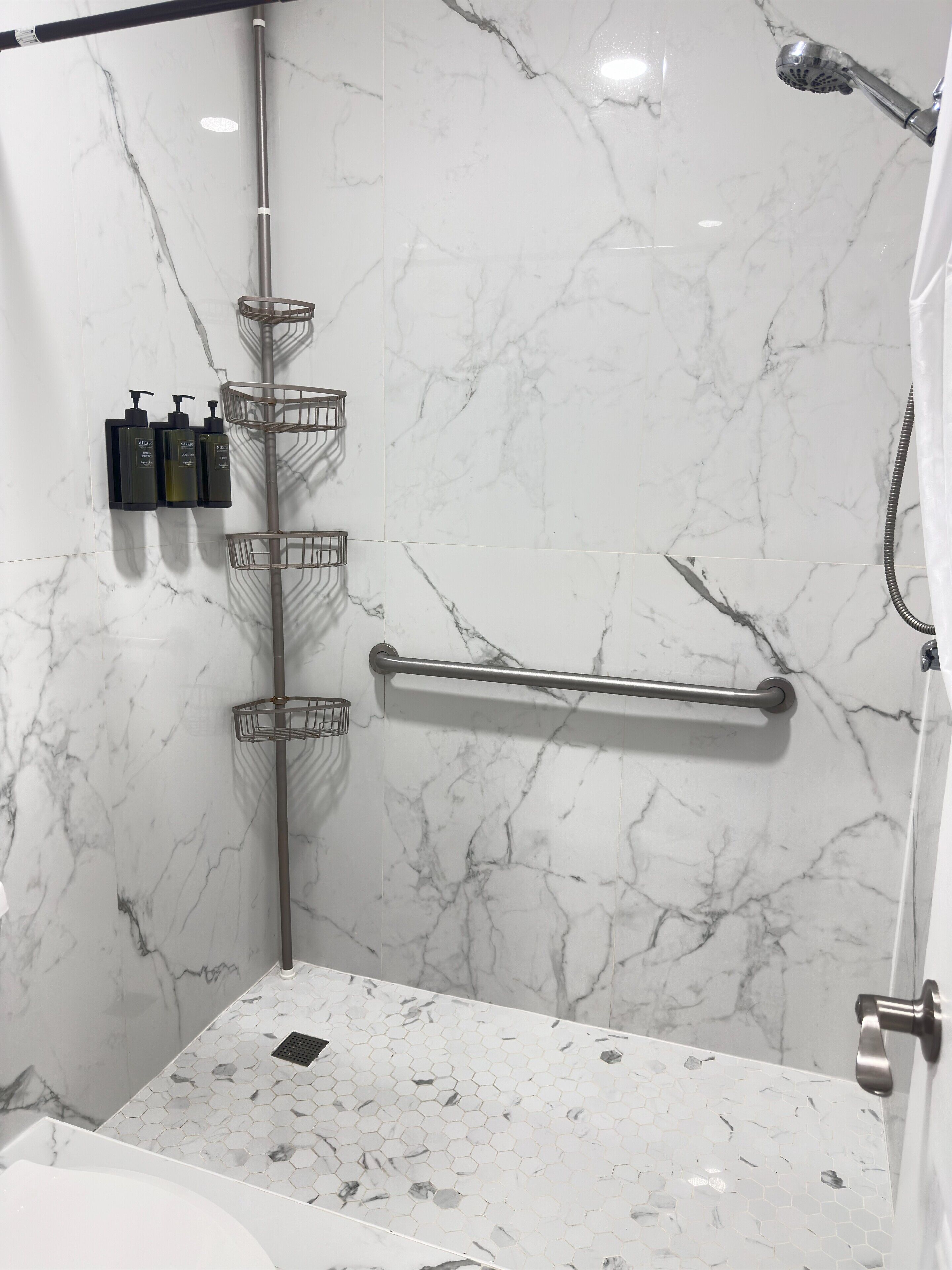 Une salle de bain avec un mur en marbre, une douche, des toilettes et un lavabo.