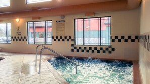 A spa area with a hot tub, tiled flooring, and a window with a view of a building outside. - White Oak Inn & Suites (Deer River)