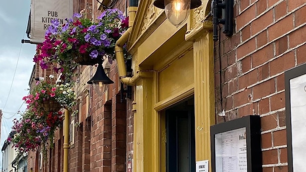 A pub named KING WILLIAM IV with hanging flower baskets and a yellow door. - King William IV (Totnes)