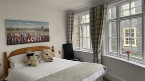 A bedroom with a bed, a painting, a window with curtains, and a desk. - King William IV (Totnes)