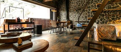 A rustic interior with a stone wall, wooden furniture, and a staircase.