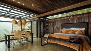 Quarto moderno com uma cama grande, piso de madeira e um espaço de refeições com móveis de vime.