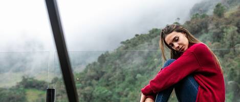 A person sitting on a wooden bench with a view of a mountainous landscape.