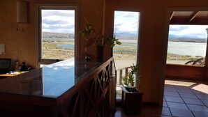 Una cocina con una isla grande, vista a un lago y un balcón con vista a las montañas.