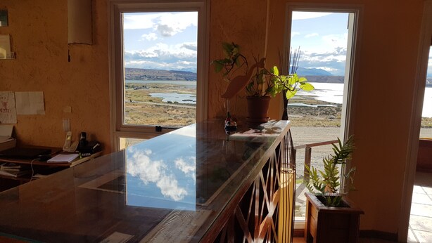 Una cocina con una isla grande, dos ventanas que ofrecen vistas a un lago y montañas, y una planta en maceta sobre la isla.