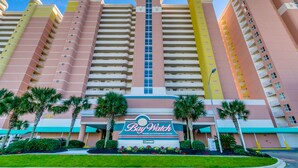 A multi-story hotel with a prominent 'Bay Watch' sign, featuring balconies and a central vertical window. - Watch Resort by Condo-World (North Myrtle Beach)
