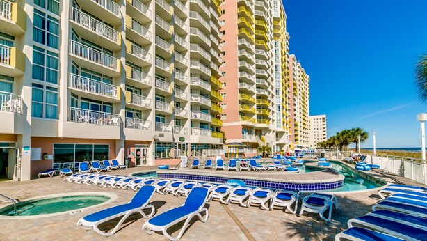 A hotel pool area with sun loungers and a circular hot tub. - Watch Resort by Condo-World (North Myrtle Beach)