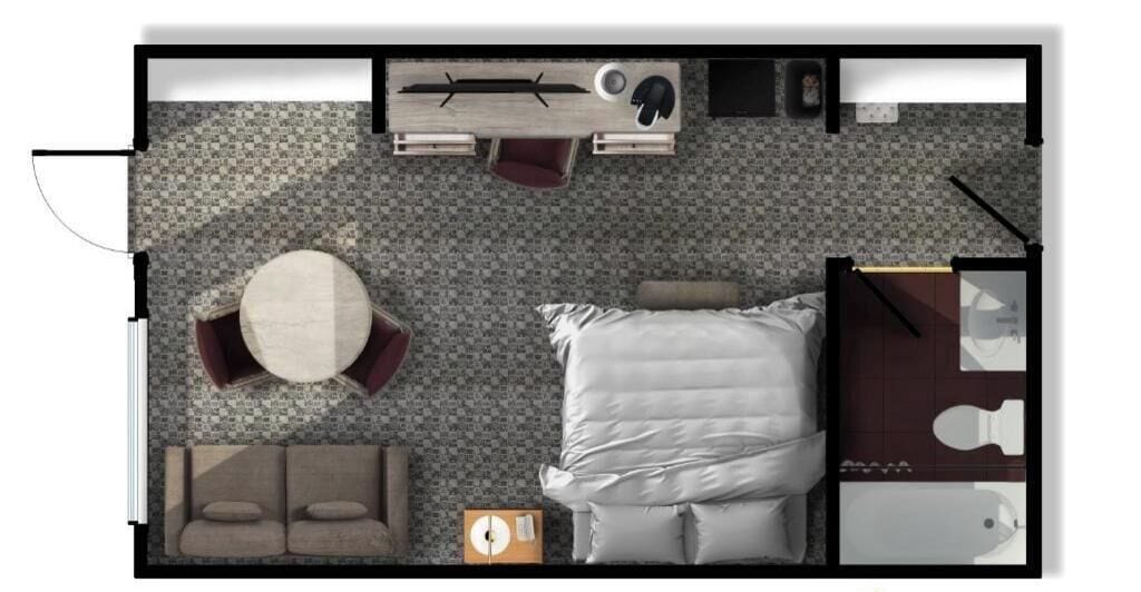 A hotel room with a bed, a round table with chairs, a sofa, a small desk, and a bathroom.