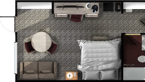 A hotel room with a bed, a round table with chairs, a sofa, a desk with a chair, and a bathroom with a toilet and sink. - Balmer Hotel (Red Lake)