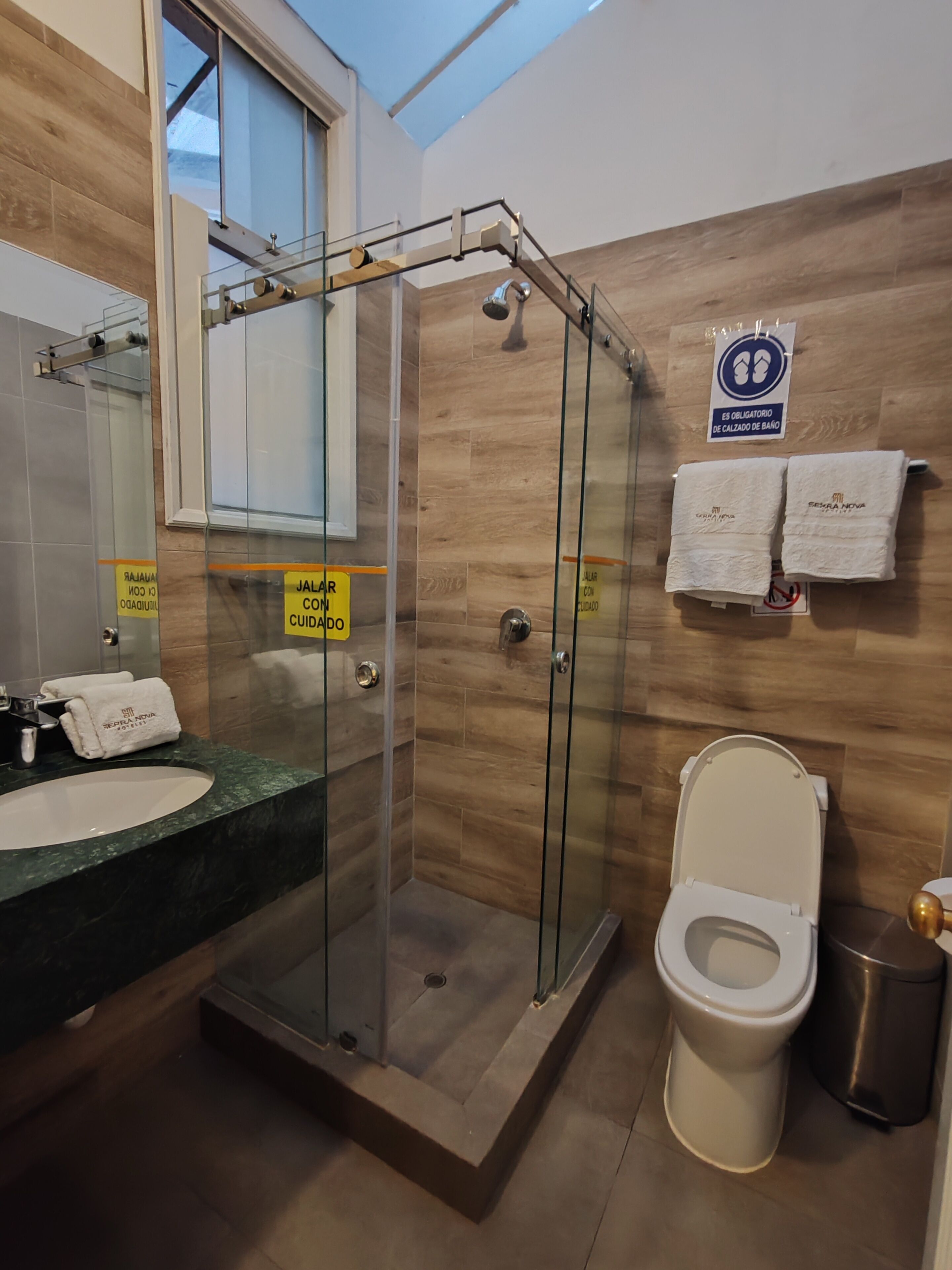 A modern bathroom with a glass-enclosed shower, a sink with a marble countertop, and a toilet.