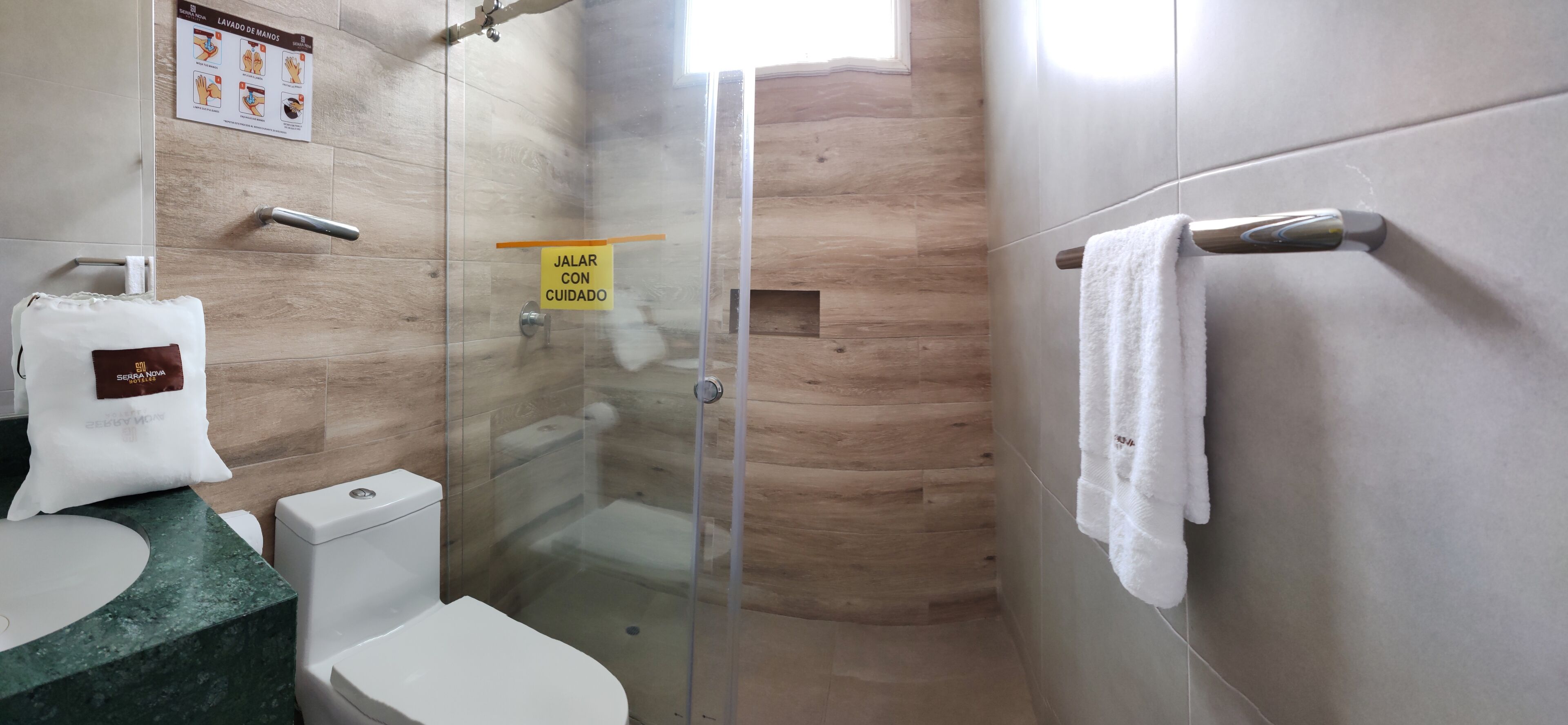 A modern bathroom with a glass shower enclosure, a toilet, a sink with a marble countertop, and a towel rack.