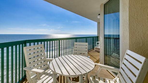 A balcony with a table and chairs, overlooking a beach. - Ashworth by Condo-World (North Myrtle Beach)