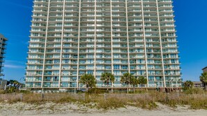 A multi-story hotel with a uniform exterior, balconies, and a beach view. - Ashworth by Condo-World (North Myrtle Beach)