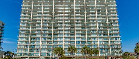 A multi-story hotel with a uniform exterior, balconies, and a beach view.
