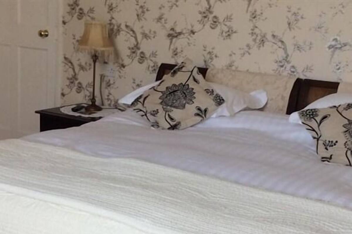A neatly made bed with floral patterned pillows and a white duvet.