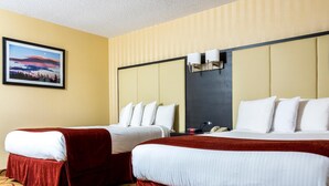 Ein Hotelzimmer mit zwei Betten, einem großen Fenster mit Blick, einem Bild an der Wand und einem gemusterten Teppich.