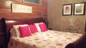 Un dormitorio con cabecera de madera, colcha estampada con flores y dos cuadros en la pared.