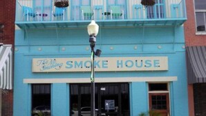 Un edificio con un letrero que dice "The No Smoking Smoke House" y el año "1904" sobre la entrada.