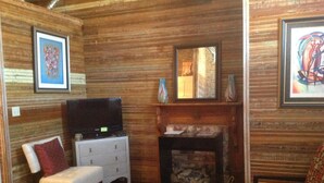 Una sala de estar acogedora con paneles de madera, una chimenea, un televisor y un sillón estampado.