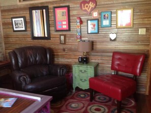 A room with a brown leather chair, a red chair, a green side table, and a patterned carpet. - The Main Street Hotel (Yazoo City)