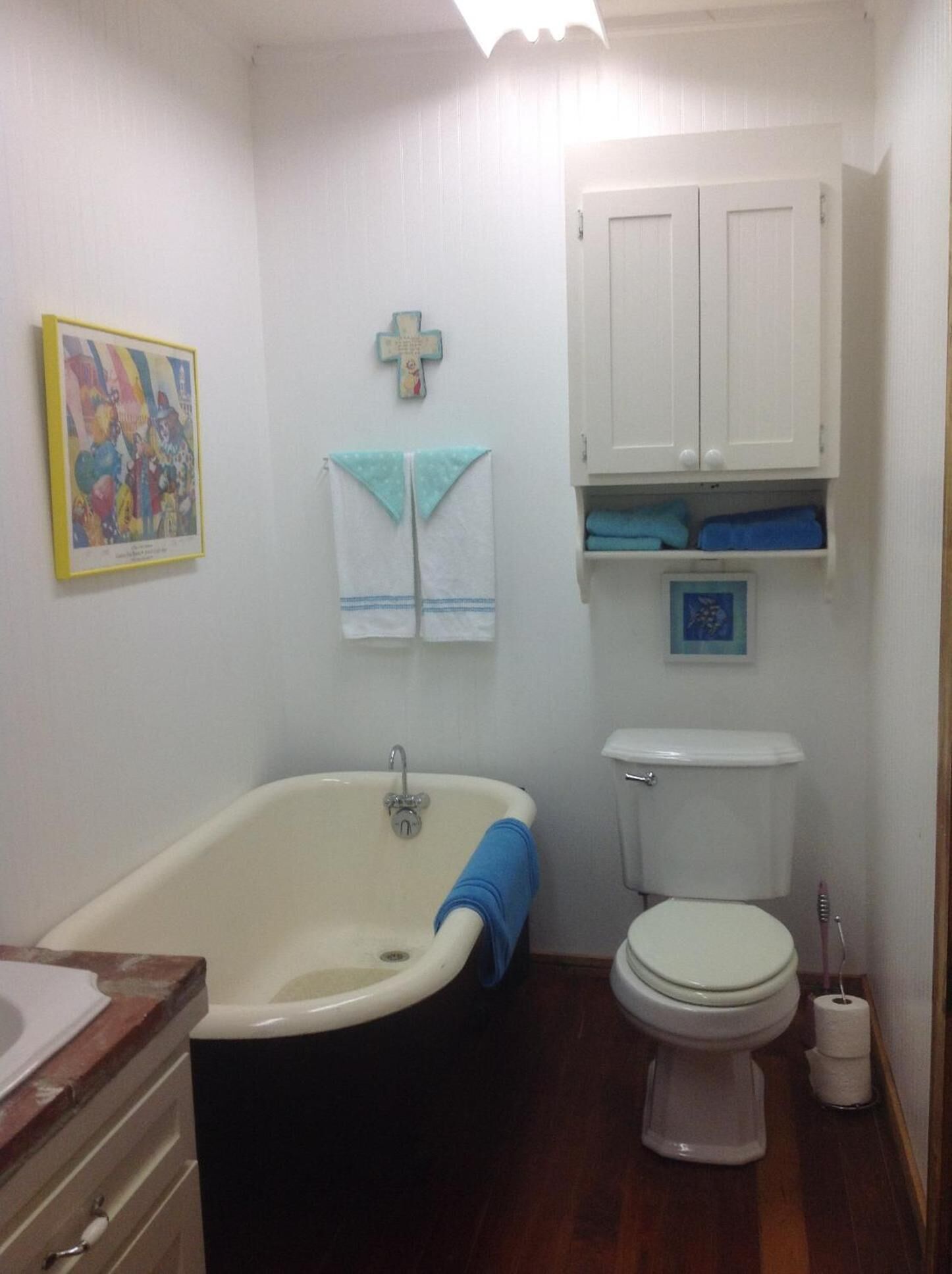 Une salle de bain avec une baignoire, des toilettes et un meuble au-dessus des toilettes.