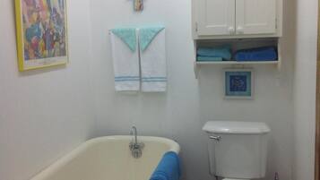 Une salle de bain avec une baignoire, des toilettes et un meuble au-dessus des toilettes.