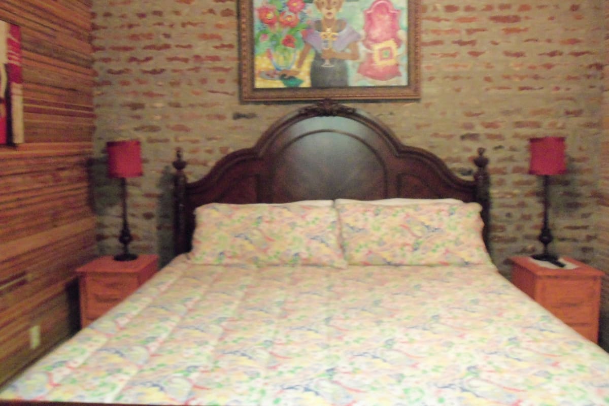 Ein Schlafzimmer mit einem hölzernen Kopfende, einer blumigen Bettdecke und zwei Nachttischlampen.