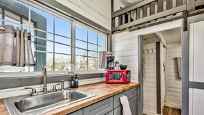 A kitchen with a wooden countertop, stainless steel sink, and a red microwave. - West Walker Motel (Coleville)