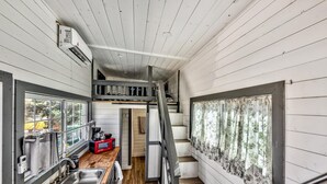 A compact kitchen with a wooden countertop, a built-in sink, and a red microwave. A staircase leads to an upper level. - West Walker Motel (Coleville)