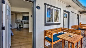 A wooden deck with benches and tables, a kitchen area visible through an open door, and a sign indicating room number 7B. - West Walker Motel (Coleville)