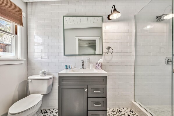 A bathroom with a toilet, sink, vanity, and shower area. - West Walker Motel (Coleville)